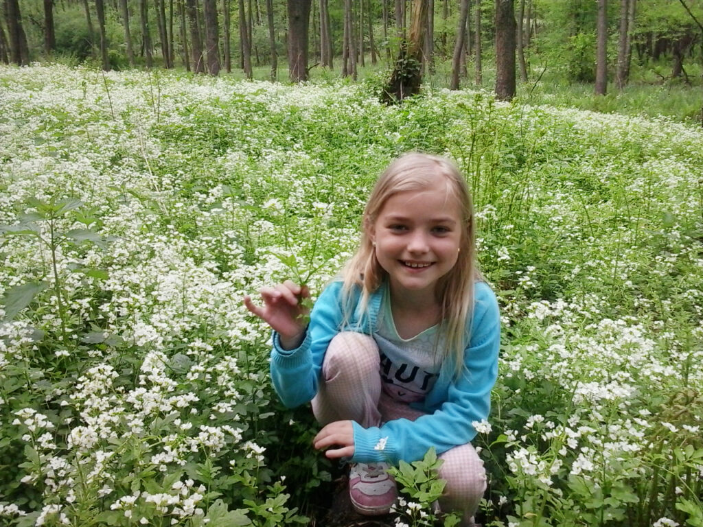 Uśmiechnięta dziewczynka na łące wśród kwiatów