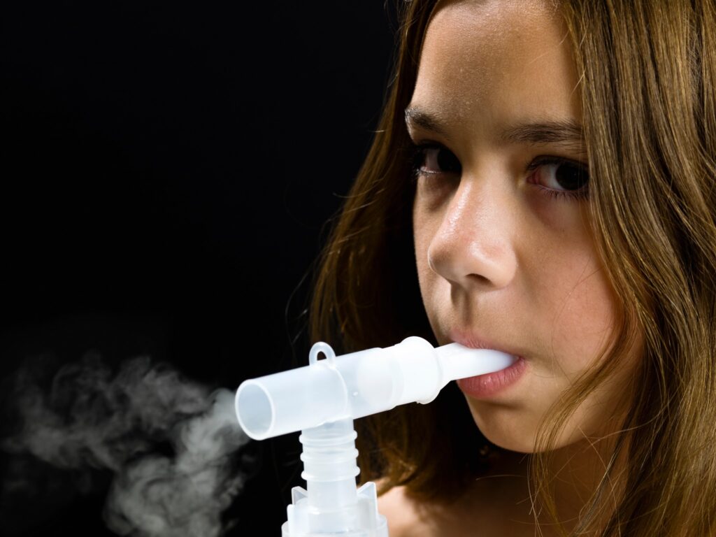 Dziewczynka z nebulizatorem w ustach