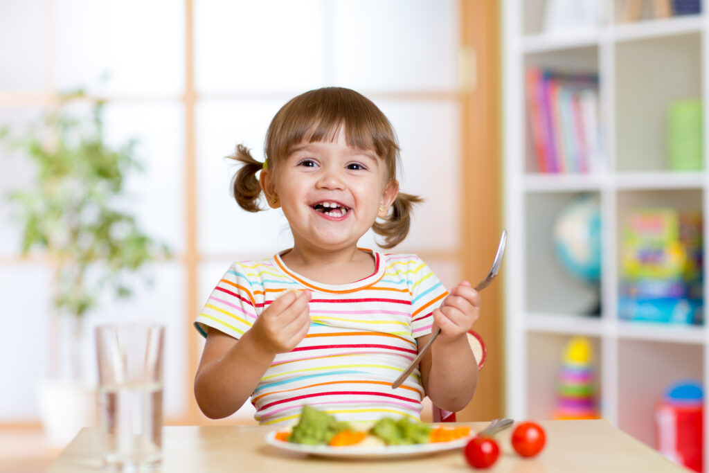 Szczęśliwa dziewczynka jedząca warzywa. Zdrowe odżywianie dla dzieci